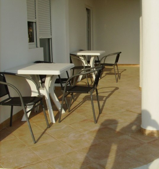Geräumige Terrasse mit Kunststoffmöbeln in einem Haus in Šušanj, Montenegro: Fliesenboden und helle Fassadengestaltung.