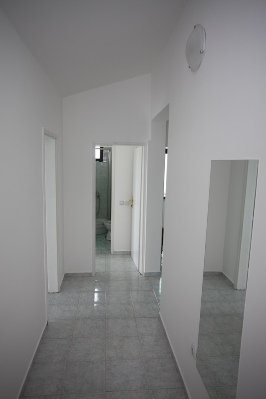 Heller Flur mit Fliesenboden und Spiegel im Haus, Stadt Dobri Vody, Montenegro. Blick auf den Eingang zum Badezimmer.