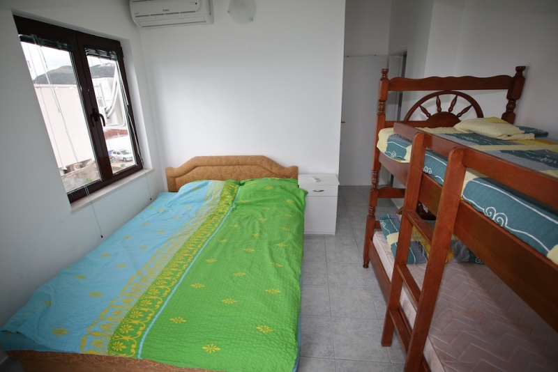 Schlafzimmer in einem Haus in Dobri Vody, Montenegro: Doppelbett, hölzernes Etagenbett, Blick aus dem Fenster.