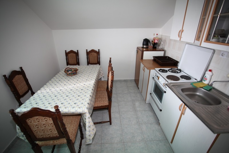 Küche mit Essbereich in einem Haus in Dobri Vody, Montenegro: helle Möbel, Herd und klassische Holzmöbel.