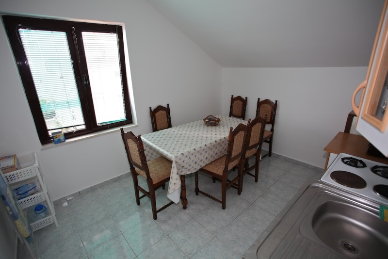 Küche mit Essbereich in einem Haus in Dobri Vody, Montenegro: Esstisch, Stühle, Herd und Spüle im Dachgeschoss.
