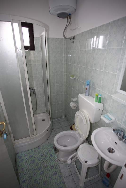 Badezimmer in einem Haus in Dobri Vody, Montenegro: Duschkabine, Sanitäranlagen, helle Fliesen und Boiler.