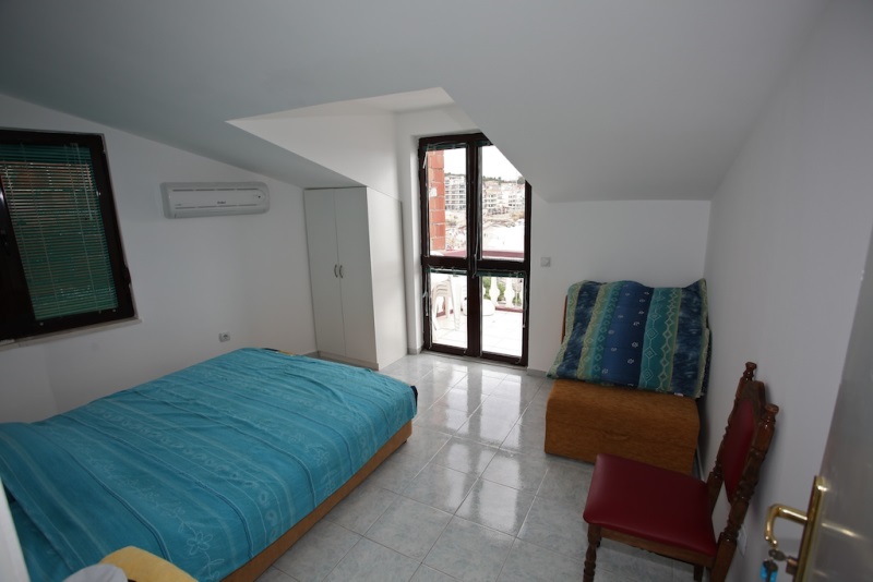 Schlafzimmer in einem Haus in Dobri Vody, Montenegro: Doppelbett, Kleiderschrank, Zugang zum Balkon mit Meerblick und Fliesenboden.