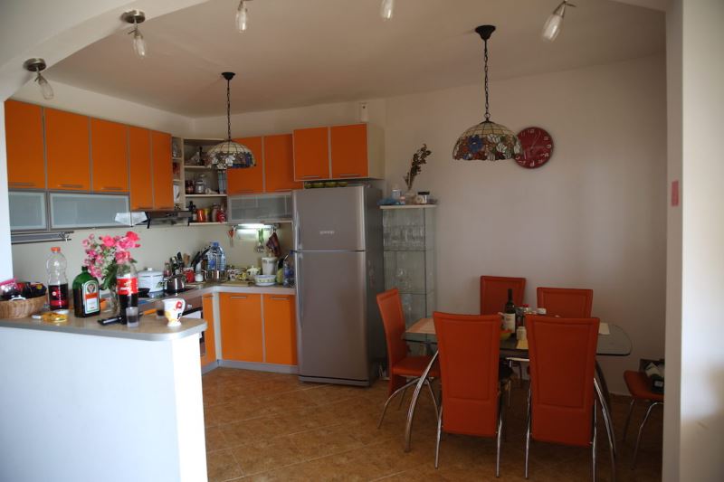 Küche mit orangefarbener Einbauküche und Essbereich im Haus, Dobri Vody, Montenegro. Innenraum mit heller Möblierung.