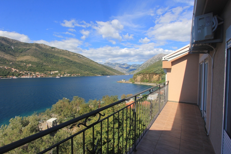 Balkon der Villa in Lepetani, Montenegro, mit Panoramablick auf die Bucht von Kotor, die Berge und gefliestem Boden.