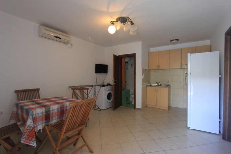 Wohnzimmer mit Küche in einer Villa in Lepetani, Montenegro: Essbereich, helle Möbel, Haushaltsgeräte und Badezimmer.