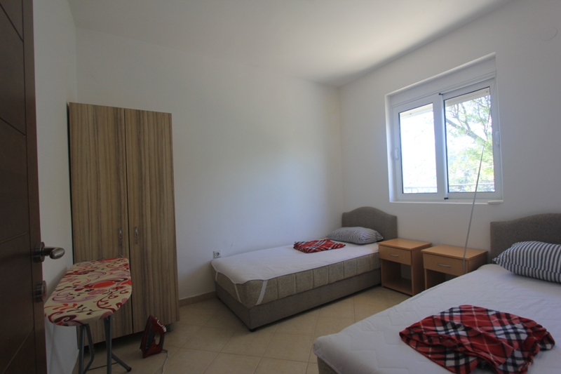 Helles Schlafzimmer mit zwei Betten, Kleiderschrank und Fenster in einer Villa in Lepetane, Montenegro. Gemütliches möbliertes Zimmer.