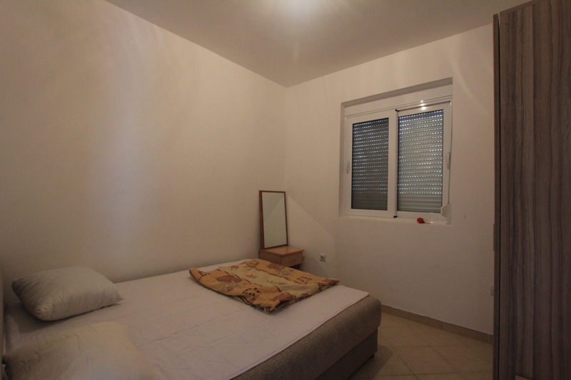 Helles Schlafzimmer mit Doppelbett und Kleiderschrank in einer Villa in Lepetani, Montenegro, mit Fenster und Rollläden.