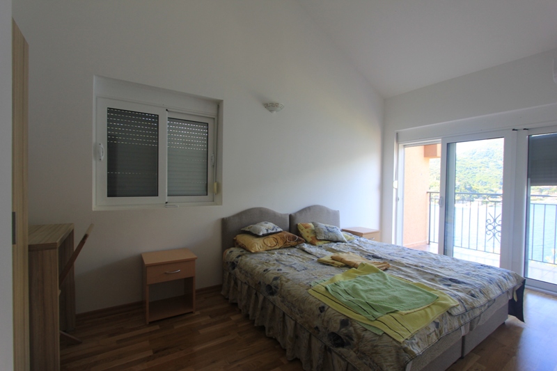 Schlafzimmer mit Doppelbett und Zugang zum Balkon mit Meerblick in einer Villa in Lepetane, Montenegro.
