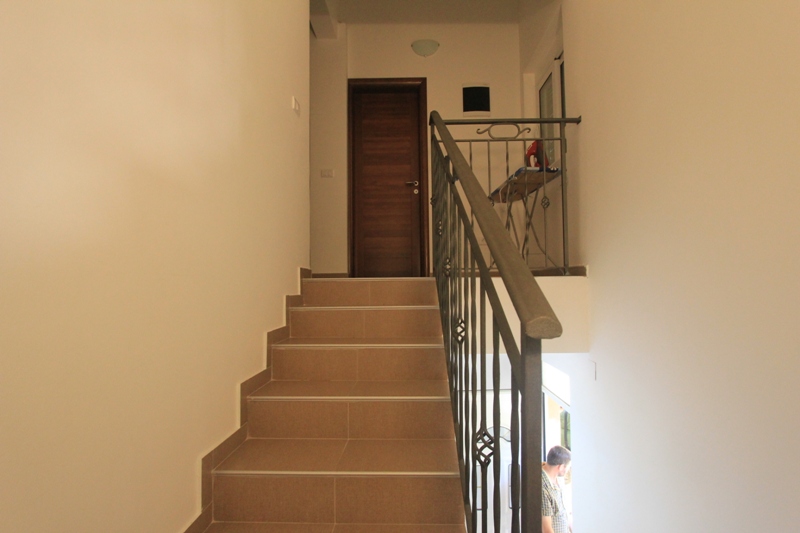 Treppe mit schmiedeeisernem Geländer und heller Ausstattung im Interieur einer Villa in Lepetani, Montenegro.