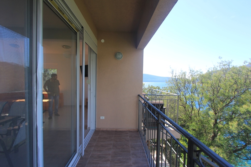 Balkon der Villa in Lepetani, Montenegro: Panoramablick auf das Meer, Fliesenboden und Zugang zum Wohnzimmer durch Glastüren.