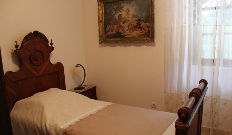 Schlafzimmer mit antikem Holzbett und Gemälde in einem Haus zum Verkauf in Strp, Montenegro.