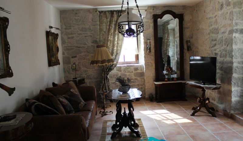 Wohnzimmer in einem Steinhaus in Strp, Montenegro: Vintage-Möbel, Wände aus Naturstein und Fliesenboden.