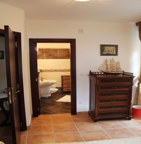 Schlafzimmer mit Holzkommode und Blick auf das Badezimmer in einem Haus zum Verkauf, Strp, Montenegro.