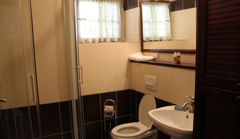Badezimmer mit Duschkabine in einem Haus in Strp, Montenegro: Fliesen in Schwarz-Weiß-Tönen, Spiegel und Sanitäranlagen.