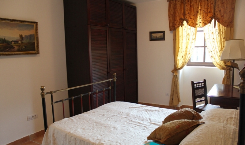 Gemütliches Schlafzimmer mit Bett und Holzschrank in einem Haus in Strp, Montenegro. Klassisches Interieur mit Gemälden.