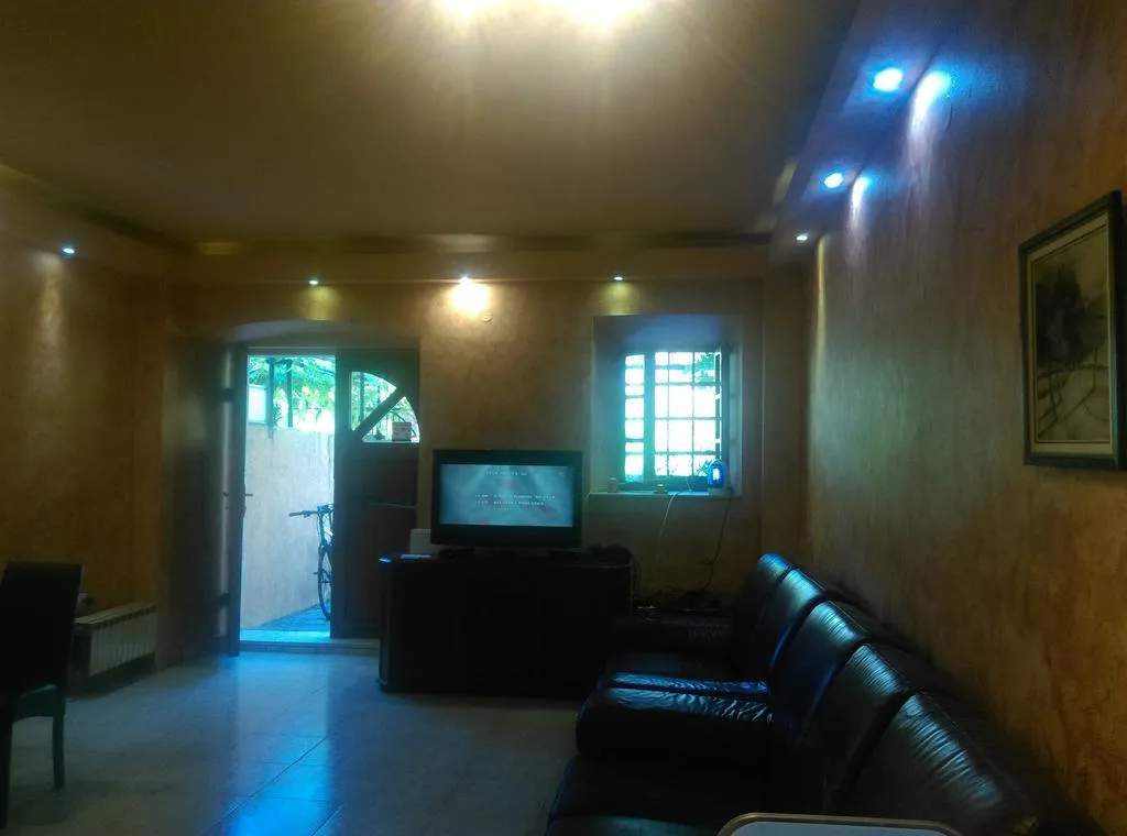 Wohnzimmer mit Ledersofa und TV in einem Haus in Dobrota, Montenegro: gemütliches Interieur mit Spotbeleuchtung und Ausgang zum Hof.
