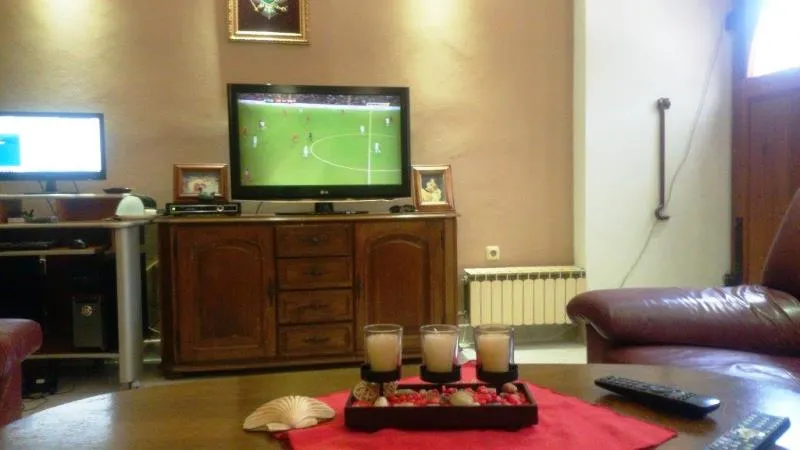 Gemütliches Wohnzimmer in einem Haus in Dobrota, Montenegro: Holz-TV-Schrank, Ledermöbel und Couchtisch mit Kerzen.