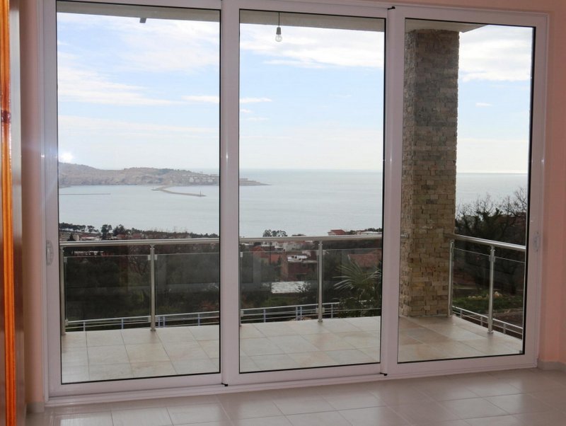 Karadağ, Šušanj’daki evin oturma odasında terasa açılan ve deniz ile dağ manzaralı panoramik pencereler.