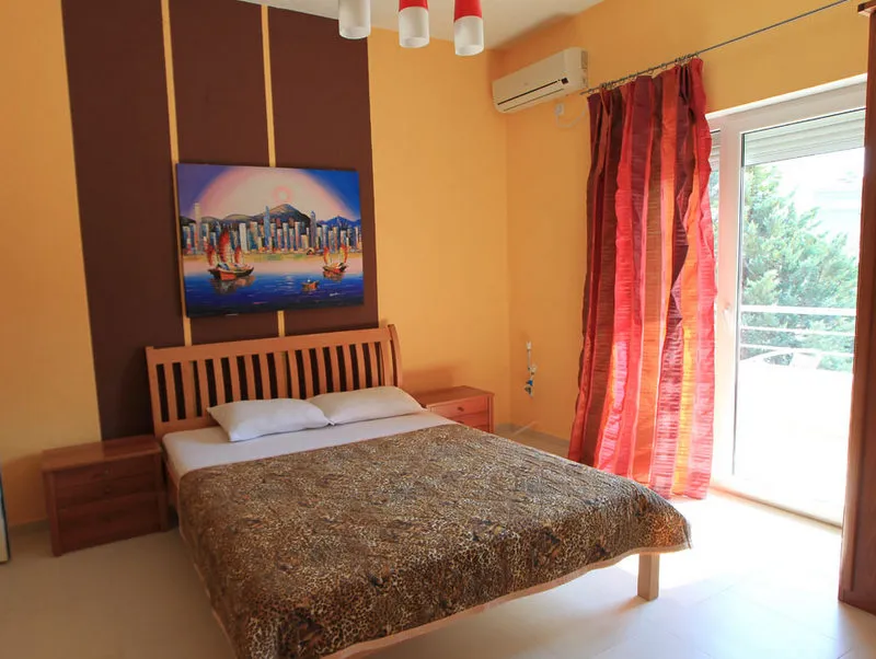 Przytulna sypialnia z łóżkiem dwuosobowym w hotelu w Budvie, Czarnogóra: jasne wnętrze, klimatyzacja i wyjście na balkon.