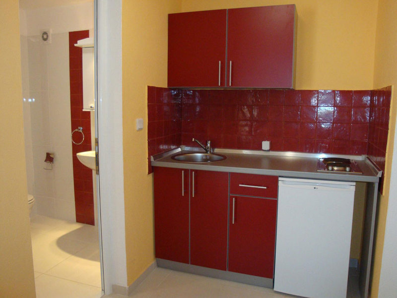 Budva, Karadağ’daki otel odasında kırmızı kapaklı kompakt mutfak ve banyo.