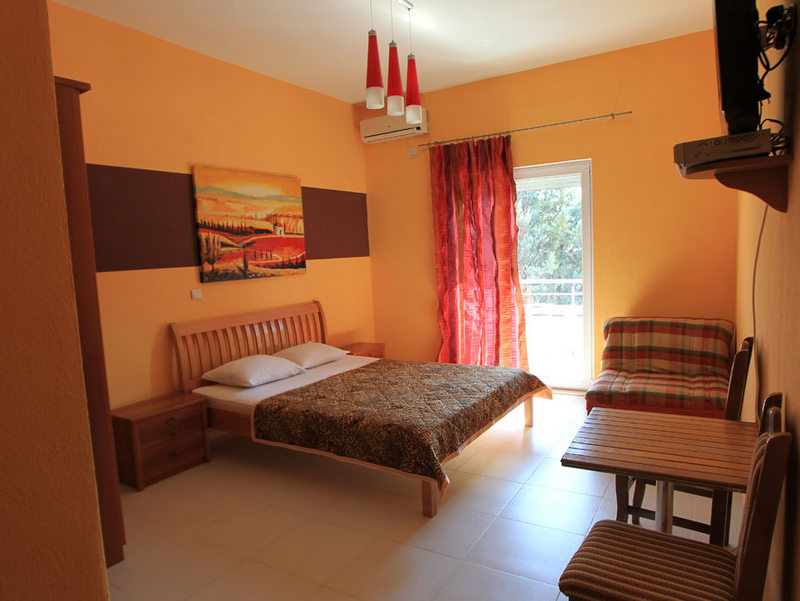 Budva, Karadağ’daki otel yatak odası: çift kişilik yatak, ahşap mobilyalar, aydınlık iç mekan ve balkona çıkış.