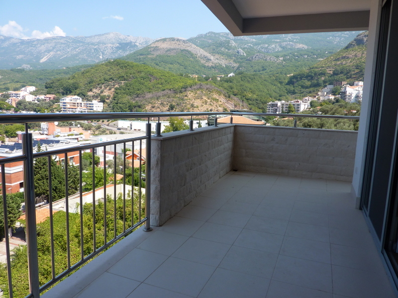 Prostran balkon sa oblogom od kamena i pogledom na planine u stanu u Pržnu, Crna Gora. Savremena čelična ograda.