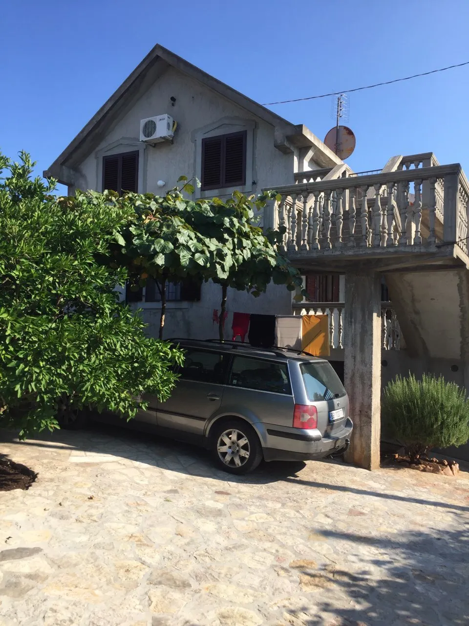 Ländliches zweistöckiges Haus mit grauem Auto, Terrasse und Grün