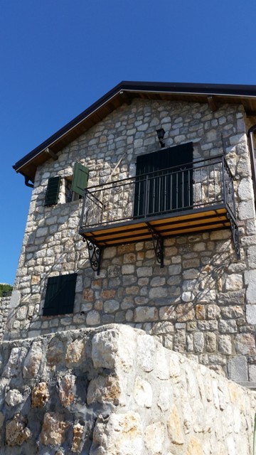 Karadağ, Šušanj’daki taş villanın cephesi: ferforje korkuluklu balkon ve pencerelerde ahşap panjurlar.