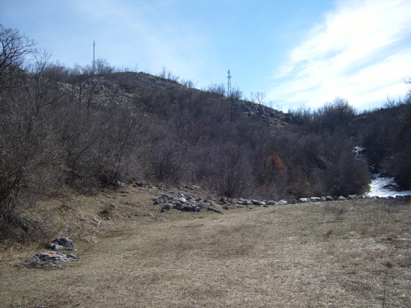 Land plot in the mountainous area of Cetinje, Montenegro: panoramic view of the hilly landscape with dry grass and forest.