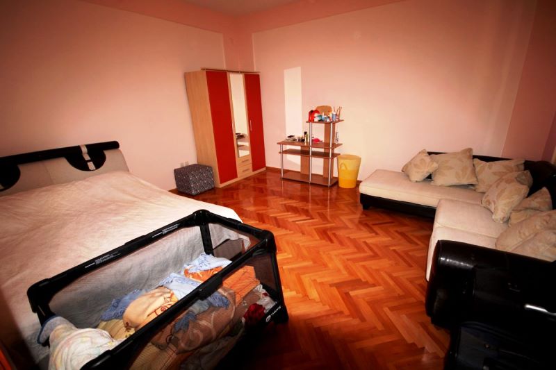 Chambre dans une maison à Đenovići, Monténégro : lit double, parc pour enfant, canapé d’angle et armoire sur parquet.