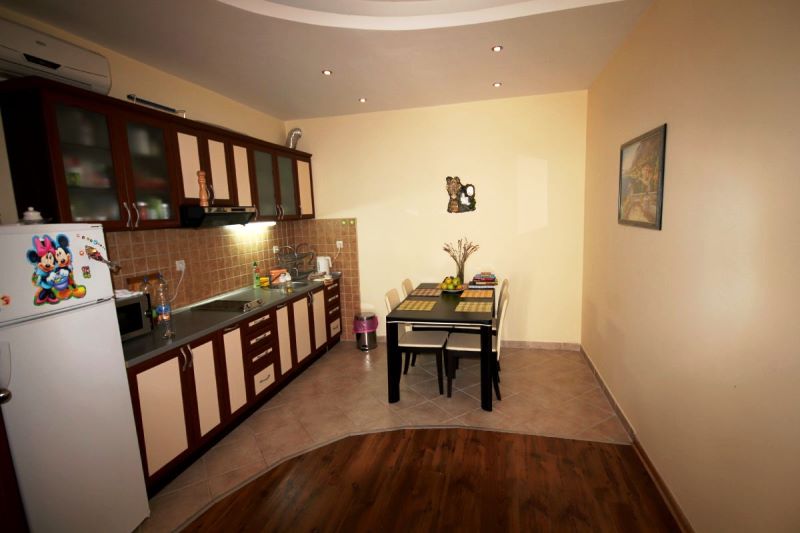 Cuisine avec coin repas dans une maison, Đenovići, Monténégro : mobilier en bois foncé, carrelage et stratifié au sol.