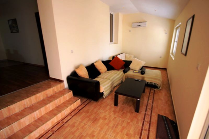 Salon avec canapé d’angle et table basse dans une maison, Genovici, Monténégro : intérieur avec carrelage et climatisation.
