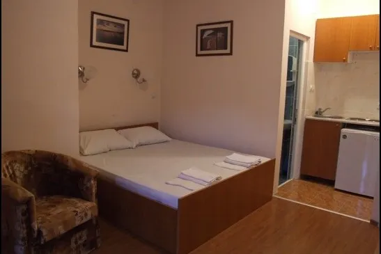 Spavaća soba u hotelu Bečići, Crna Gora: bračni krevet, fotelja, kuhinjski kutak i posebno kupatilo.