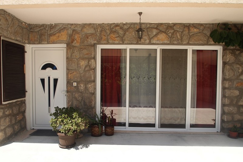 Eingang zum Hotel Nr. 844 in Bečići, Montenegro: Fassade aus Naturstein, weiße Kunststofftür und Panoramafenster.