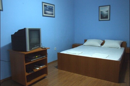 Schlafzimmer im Hotel Bečići, Montenegro: Doppelbett, Fernseher auf dem Sideboard, blaue Wände und Laminatboden.
