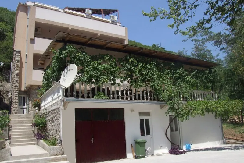 Trospratni hotel u Bečićima, Crna Gora, sa terasom obraslom vinovom lozom i kamenom fasadom.