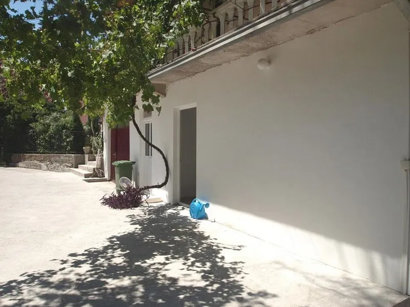 Beli fasada hotela u Bečićima, Crna Gora, sa terasom, vinovom lozom i ulazom u sobu na prvom spratu.