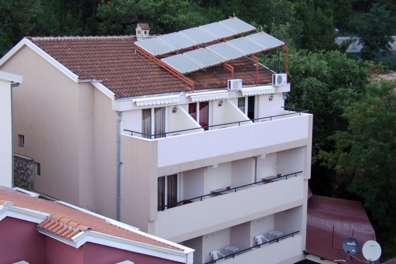 Fassade des Hotels in Bečići, Montenegro: Gebäude mit Balkonen, Ziegeldach und installierten Sonnenkollektoren.