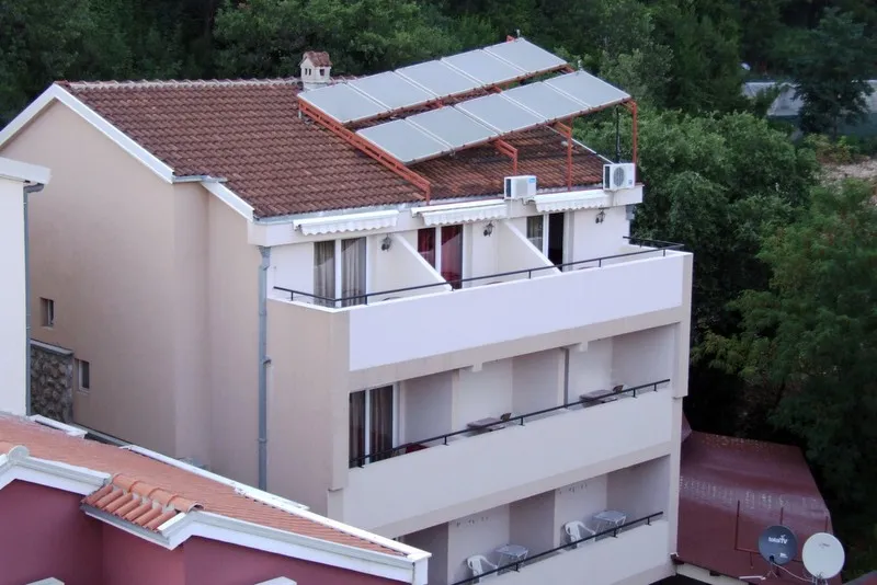 Fasada hotela u Bečićima, Crna Gora: zgrada sa balkonima, krovom od crepa i postavljenim solarnim panelima.
