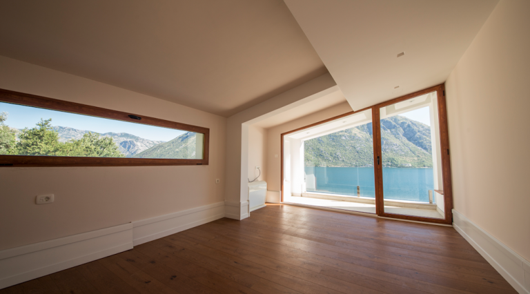 Helles Wohnzimmer mit Panoramablick auf das Meer und die Berge in einem Haus, Stoliv, Bucht von Kotor, Montenegro. Holzboden.