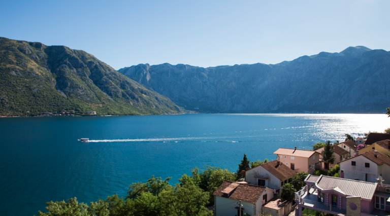 Panoramablick auf die Bucht von Kotor und die Berge vom Haus in Stoliv, Montenegro: Meer, Motorboot und Küstengebäude.