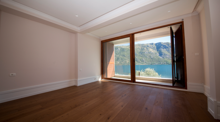 Helles Wohnzimmer mit Holzboden und Panoramablick auf das Meer und die Berge in einem Haus, Stoliv, Montenegro.