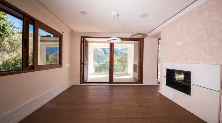 Wohnzimmer in einem Haus in Stoliv, Montenegro: Panoramablick auf die Bucht von Kotor, Kamin und Holzboden.