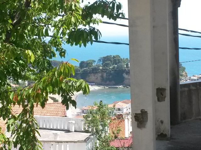 Pogled sa balkona kuće u Ulcinju, Crna Gora: panorama morskog zaliva, plaže i gradskih krovova od crepa.