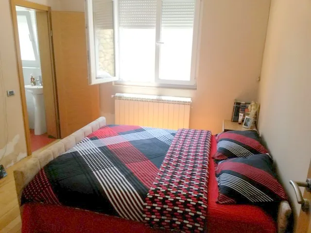 Gemütliches Schlafzimmer mit Doppelbett in einem Haus zum Verkauf in Ulcinj, Montenegro, mit Zugang zu einem separaten Badezimmer.