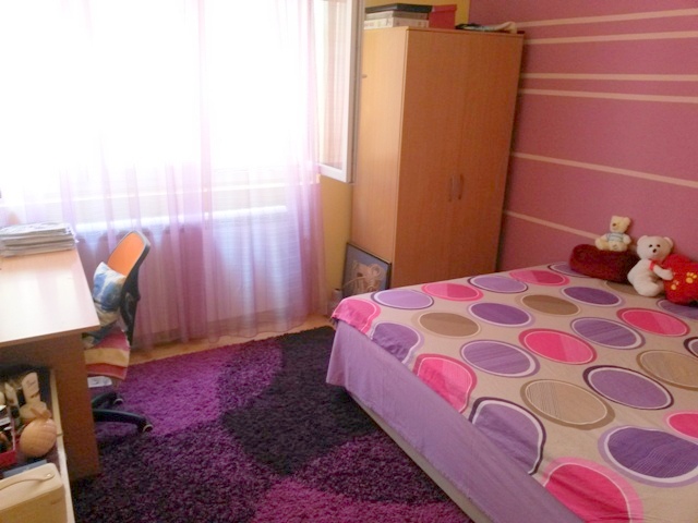 Udobna spavaća soba u kući u Ulcinju, Crna Gora: bračni krevet, radni sto, ormar i ljubičasti tepih.