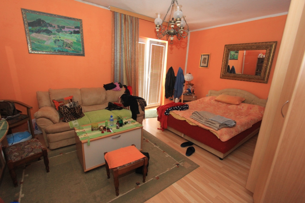 Wohnzimmer mit Doppelbett und Sofa im Haus, Radanovici, Montenegro: Innenraum mit orangefarbenen Wänden und Möbeln.