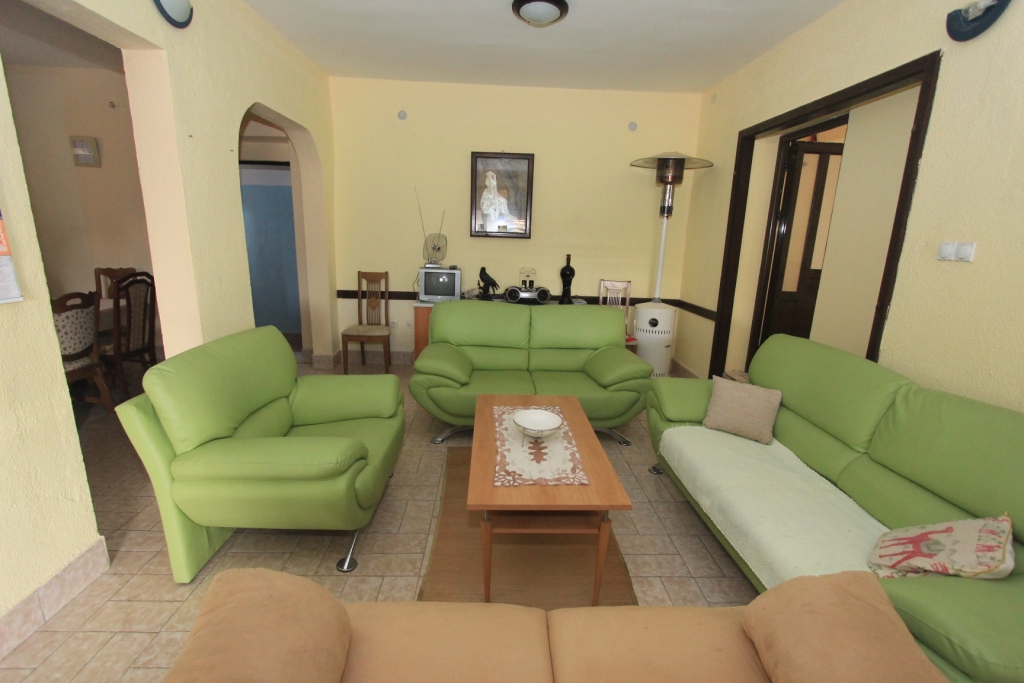 Wohnzimmer mit hellgrünen Ledersofas in einem Haus zum Verkauf, Radanovići, Montenegro: Innenraum mit Fliesenboden.