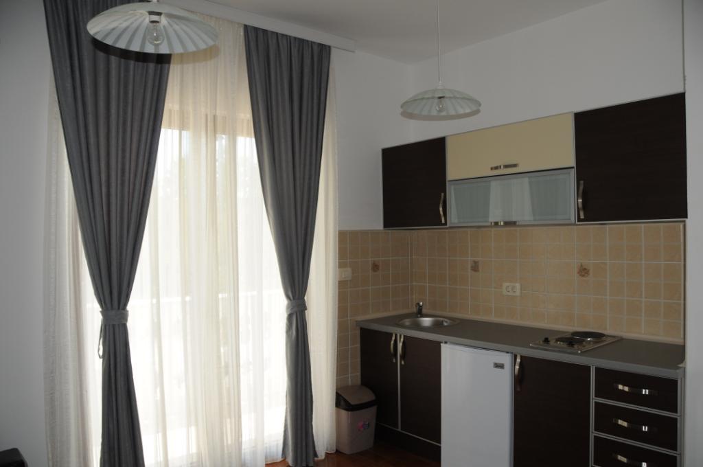 Nowoczesna kuchnia w apartamentach willi w Markovici, Czarnogóra: ciemna zabudowa, płytki i wyjście na balkon.